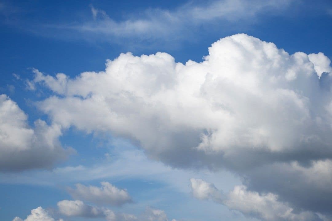 a plane flying through a cloudy blue sky