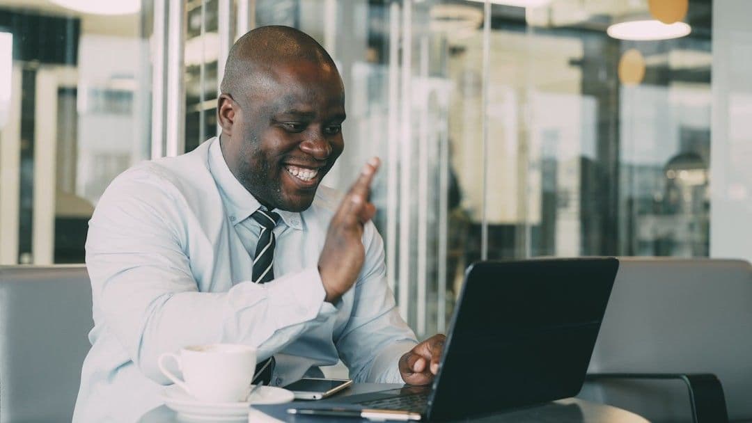 Man waving during a video call on laptop.
