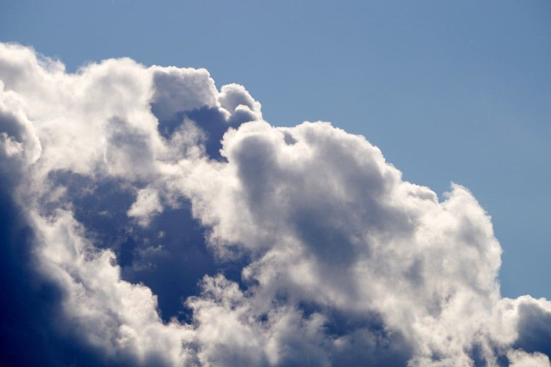 a plane flying through a cloud filled sky