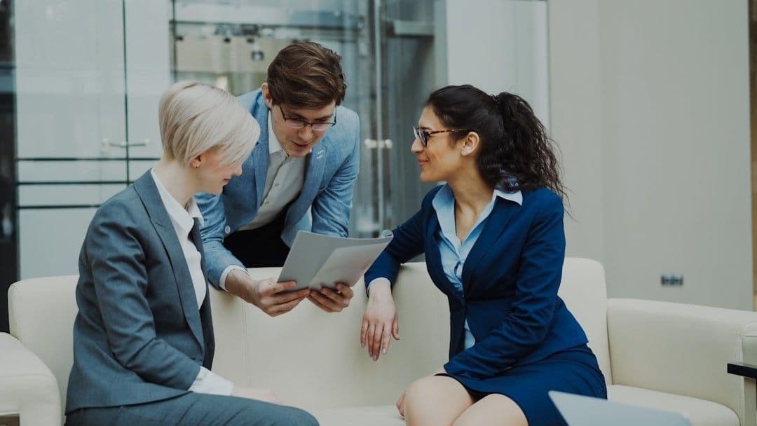 Three business people in suits discussing documents.