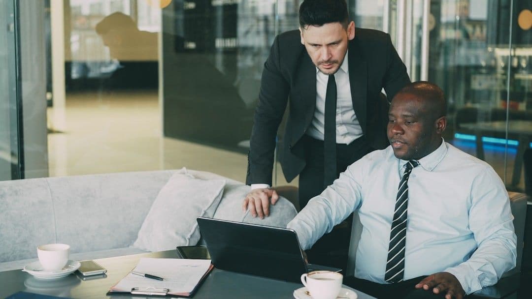 Two businessmen collaborating on a laptop in an office.