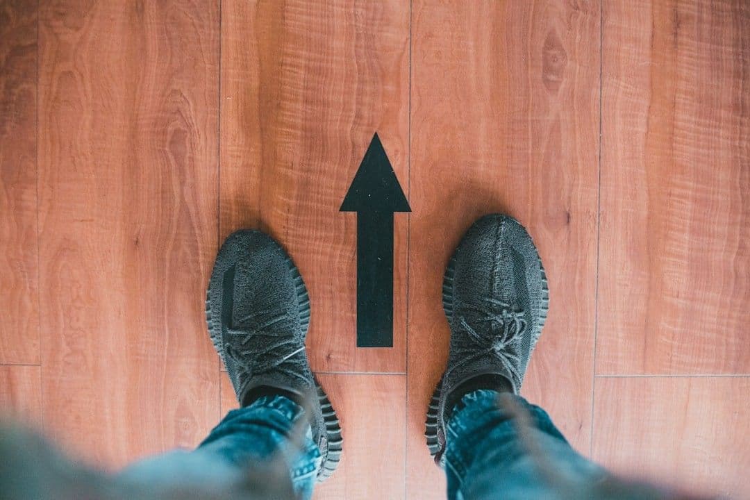 person wearing gray shoes standing on brown wooden floor