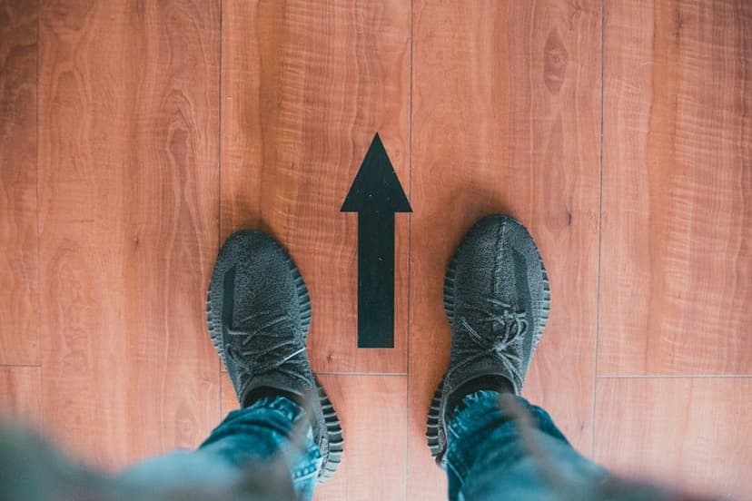 person wearing gray shoes standing on brown wooden floor