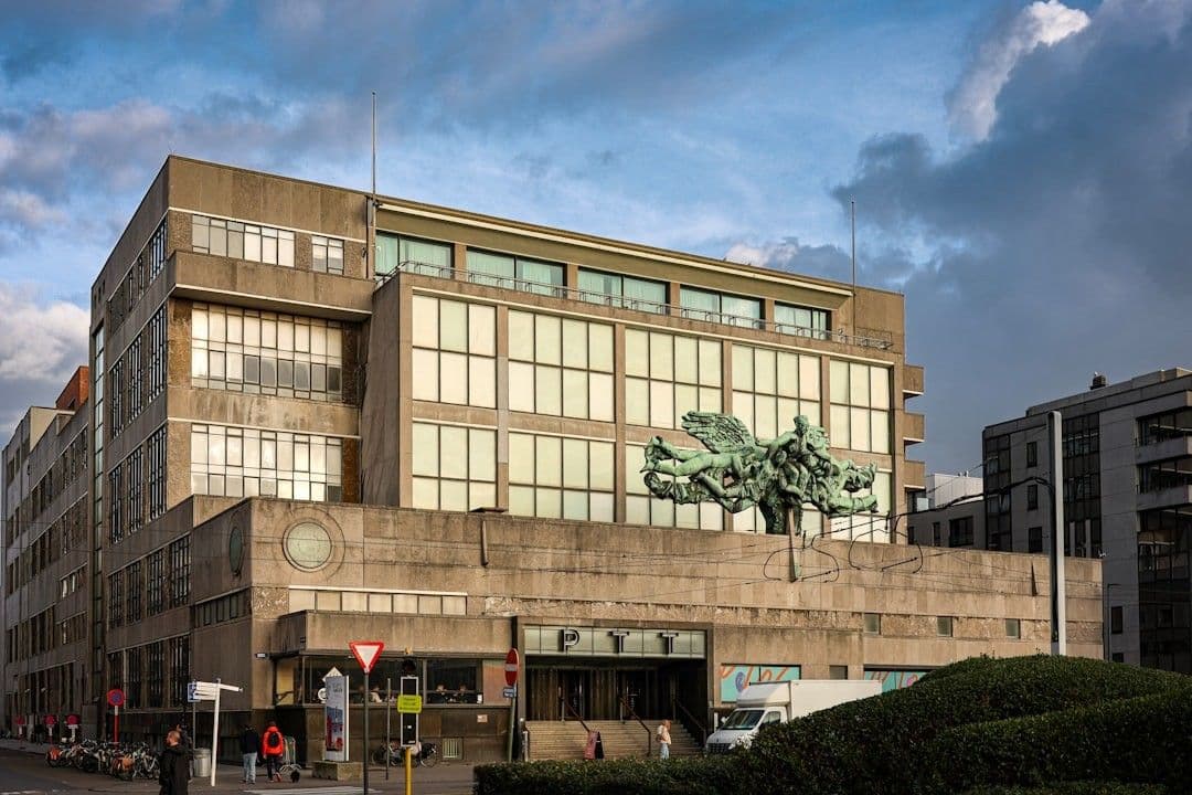Brutalist building with large windows and sculpture.