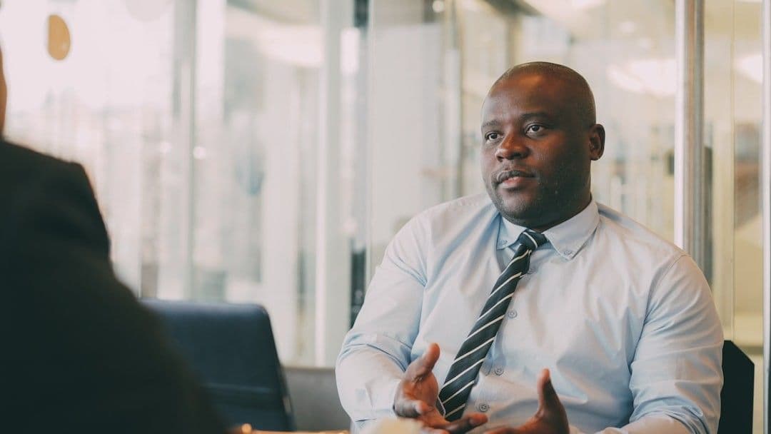 Man in a light blue shirt and tie talking.