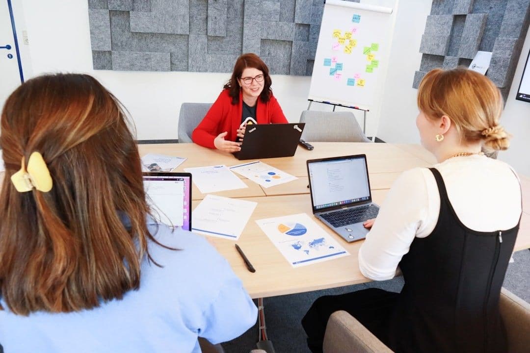a group of people sitting around a table with laptops