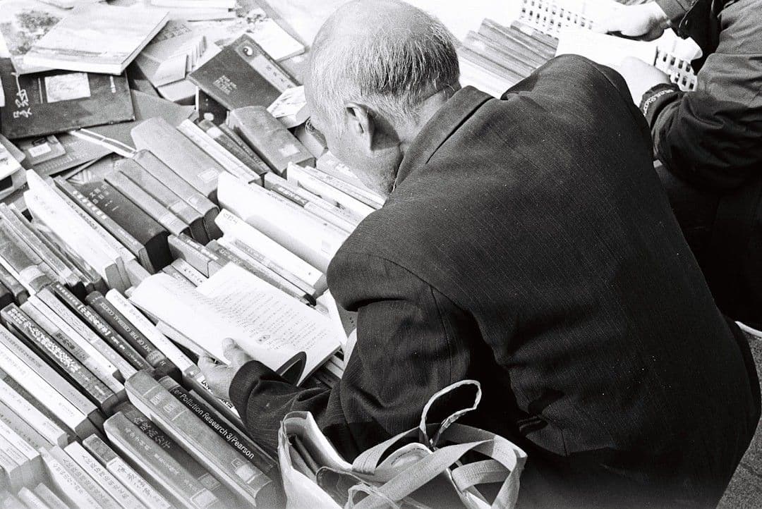a man sitting on a bench next to a pile of books