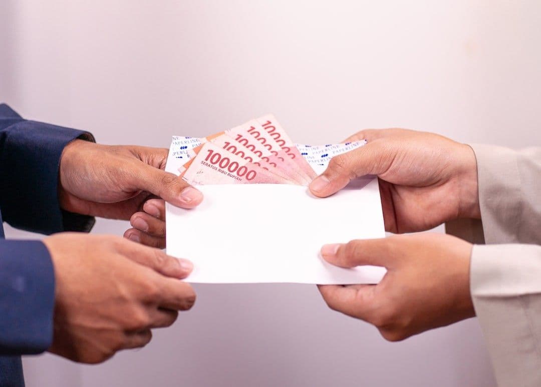 A person is giving money in an envelope.