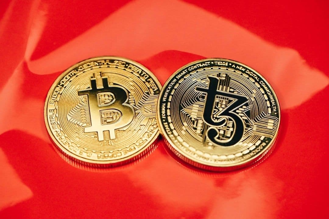 two gold bitcoins sitting side by side on a red cloth