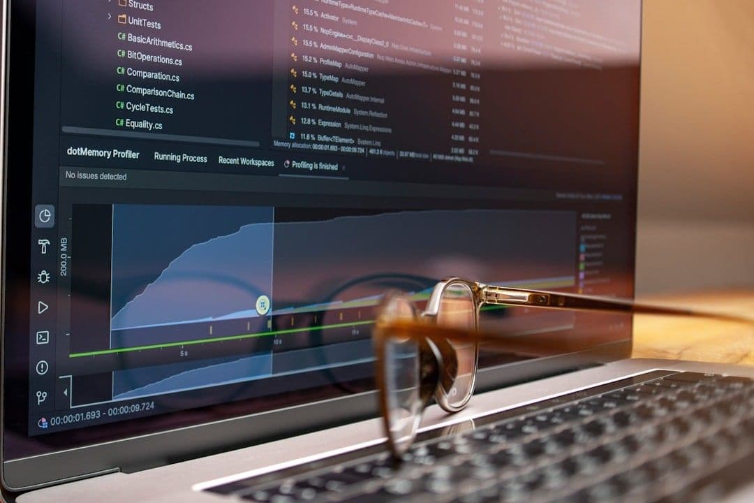 Laptop screen displaying code and graphs with glasses on keyboard